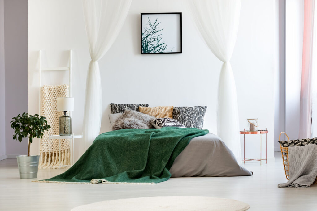 Bright bedroom with sheer curtains and a green throw